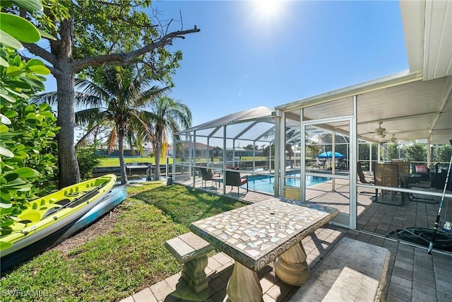 view of patio featuring ceiling fan and glass enclosure