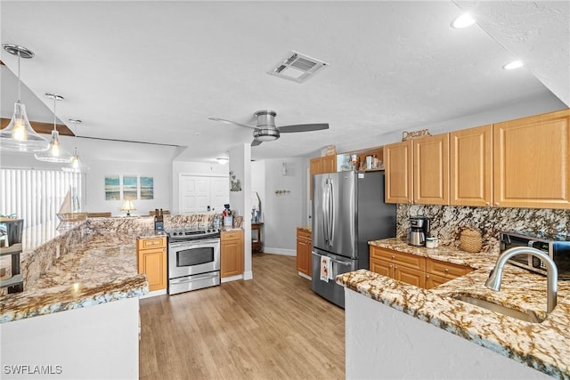 kitchen featuring pendant lighting, sink, backsplash, stainless steel appliances, and light wood-type flooring