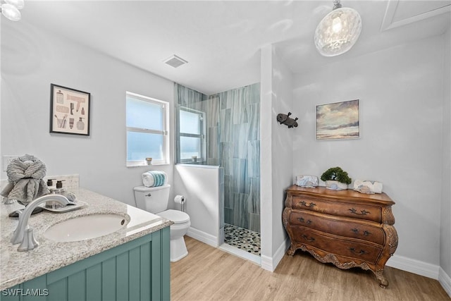 bathroom featuring tiled shower, vanity, toilet, and hardwood / wood-style floors