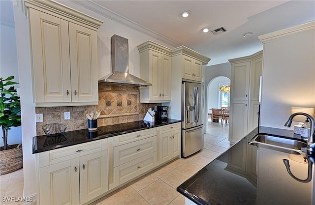 kitchen featuring wall chimney exhaust hood, sink, stainless steel fridge with ice dispenser, black electric cooktop, and cream cabinetry