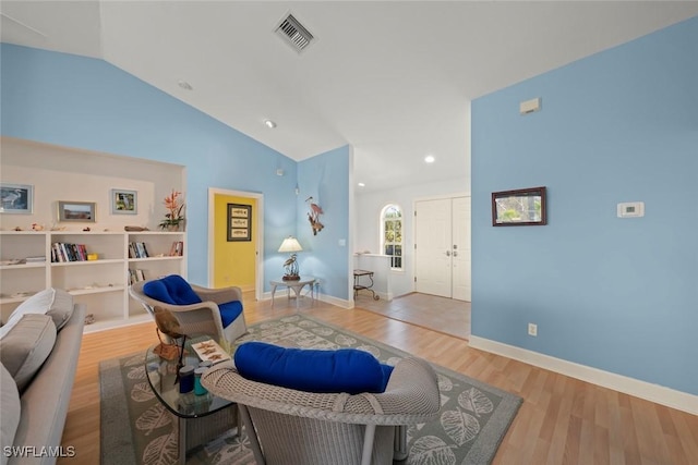 living area with lofted ceiling, light wood-style flooring, visible vents, and baseboards