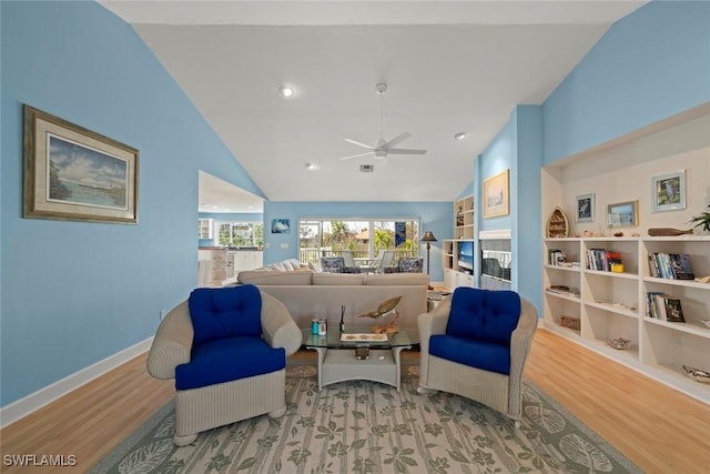 sitting room with lofted ceiling, built in shelves, light wood-type flooring, and baseboards