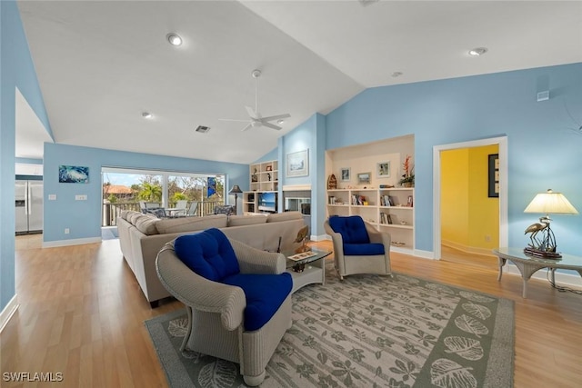 living area with visible vents, baseboards, lofted ceiling, ceiling fan, and light wood-style floors