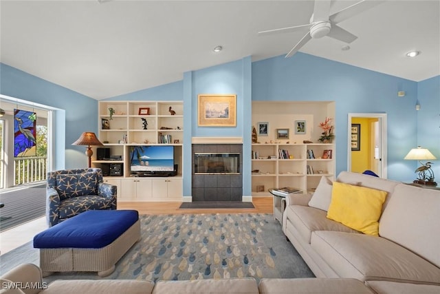 living room featuring lofted ceiling, a ceiling fan, wood finished floors, and a tile fireplace