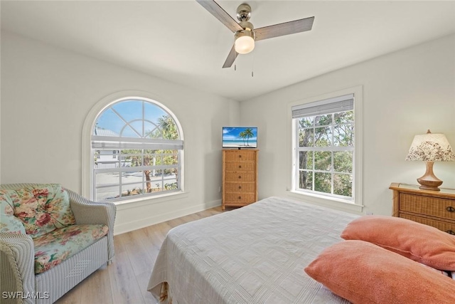 bedroom with baseboards, a ceiling fan, and light wood-style floors