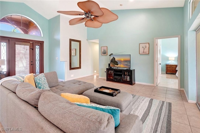 tiled living area with baseboards, a towering ceiling, and ceiling fan