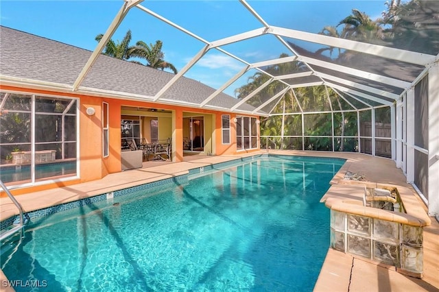 outdoor pool with glass enclosure, a patio, and ceiling fan