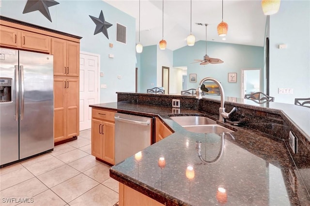 kitchen featuring decorative light fixtures, light brown cabinetry, light tile patterned floors, stainless steel appliances, and a sink