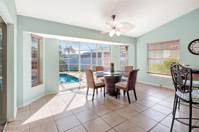 dining area with light tile patterned floors, baseboards, ceiling fan, and vaulted ceiling