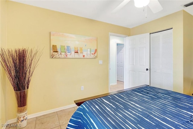 bedroom with visible vents, ceiling fan, baseboards, light tile patterned floors, and a closet