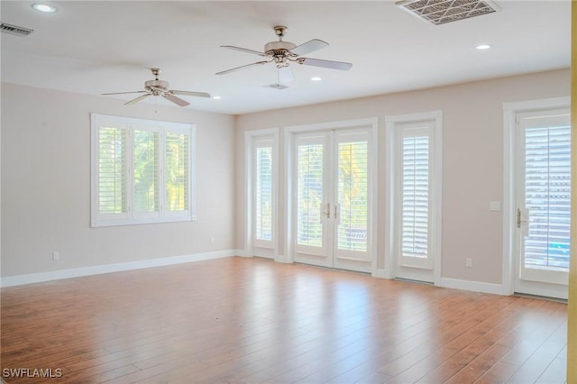 empty room featuring french doors, plenty of natural light, and light hardwood / wood-style flooring