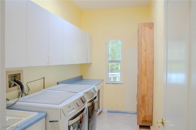 laundry room featuring cabinets, light tile patterned floors, sink, and washing machine and clothes dryer