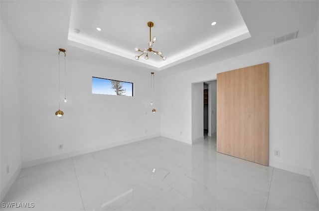 empty room with a notable chandelier and a tray ceiling