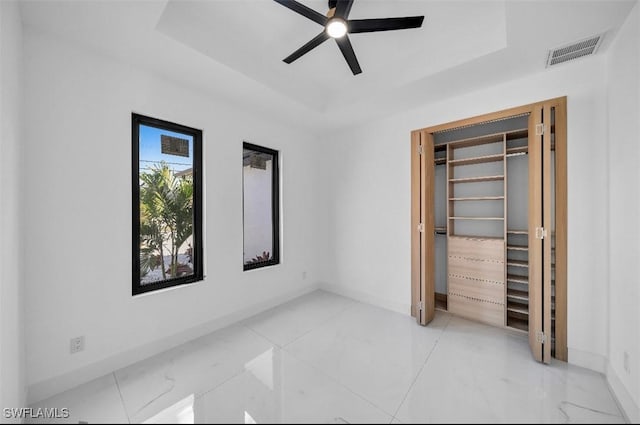 unfurnished bedroom featuring ceiling fan and a raised ceiling