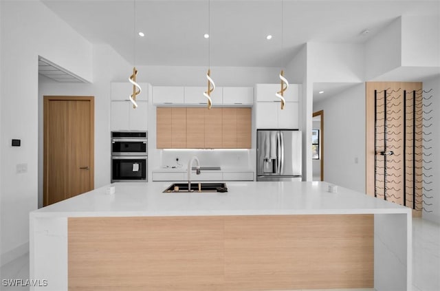 kitchen with decorative light fixtures, sink, white cabinets, a kitchen island with sink, and stainless steel appliances