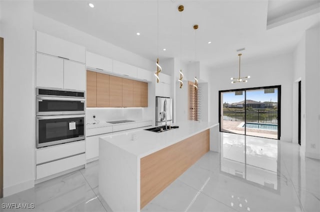 kitchen with hanging light fixtures, white cabinetry, a center island, and sink