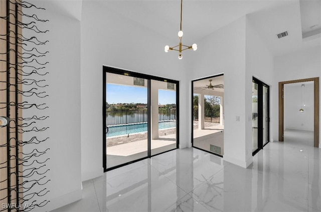 spare room with a towering ceiling, a chandelier, and a water view