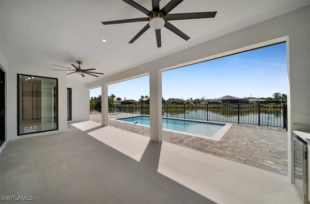 view of pool with a patio, ceiling fan, and a water view