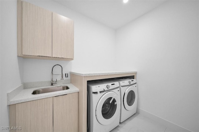 clothes washing area featuring sink, washing machine and dryer, and cabinets