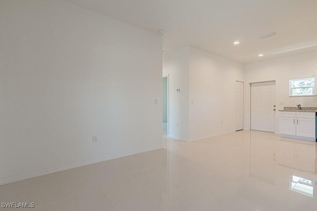 empty room featuring recessed lighting, light tile patterned flooring, a sink, and baseboards