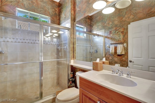 bathroom featuring vanity, a shower with door, and toilet