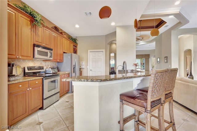 kitchen featuring stainless steel appliances, hanging light fixtures, and light stone counters