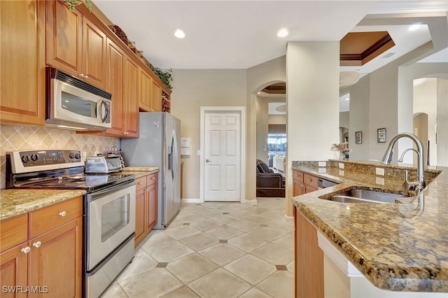 kitchen with sink, light tile patterned floors, backsplash, stainless steel appliances, and light stone countertops