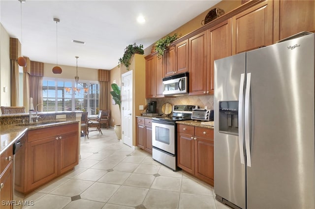 kitchen featuring stainless steel appliances, hanging light fixtures, sink, and light stone counters