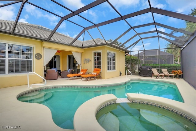 view of pool with an in ground hot tub, a patio, outdoor lounge area, and glass enclosure