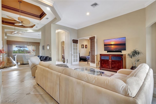 tiled living room with a raised ceiling, ornamental molding, and ceiling fan