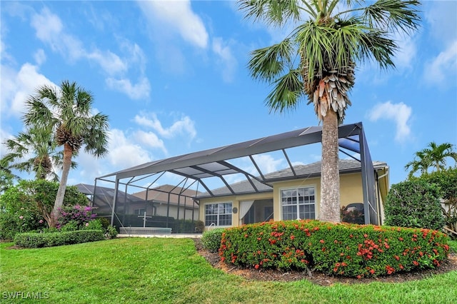 exterior space with glass enclosure and a lawn