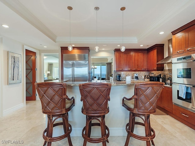 kitchen with decorative light fixtures, a tray ceiling, and stainless steel appliances