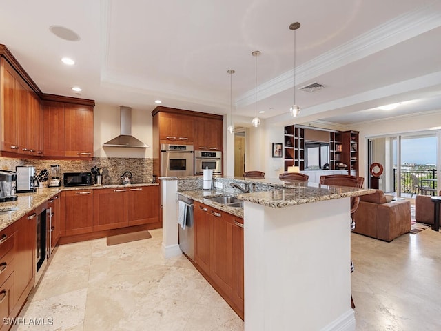 kitchen featuring a breakfast bar, decorative light fixtures, oven, ornamental molding, and wall chimney exhaust hood