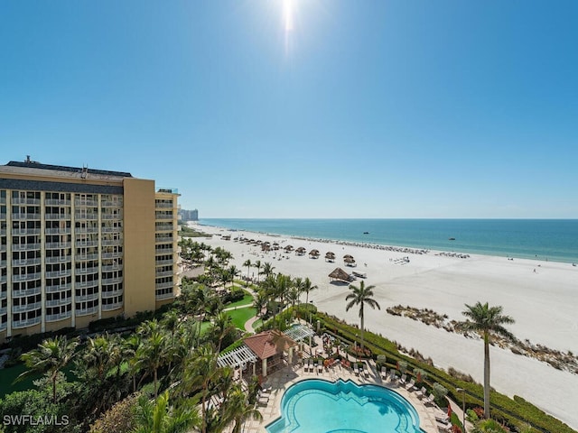 view of swimming pool with a patio area, a beach view, and a water view