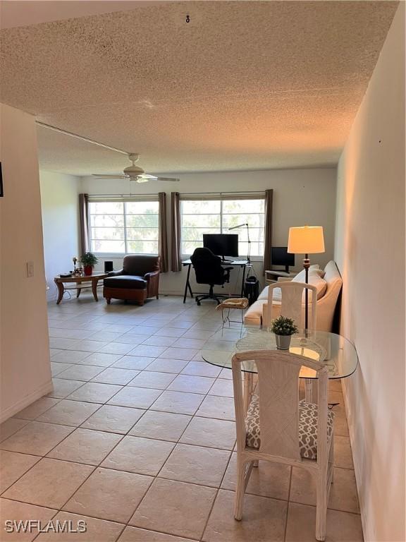 living room with a textured ceiling, light tile patterned flooring, and ceiling fan