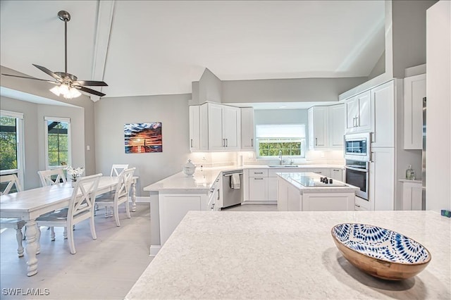 kitchen with stainless steel appliances, sink, a kitchen island, and white cabinets