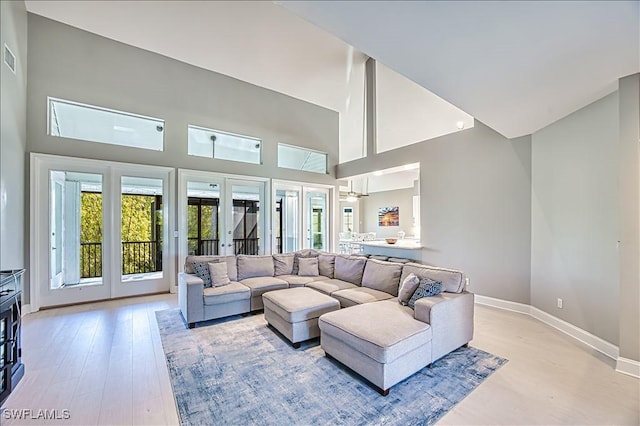 living room with french doors, a high ceiling, and light wood-type flooring