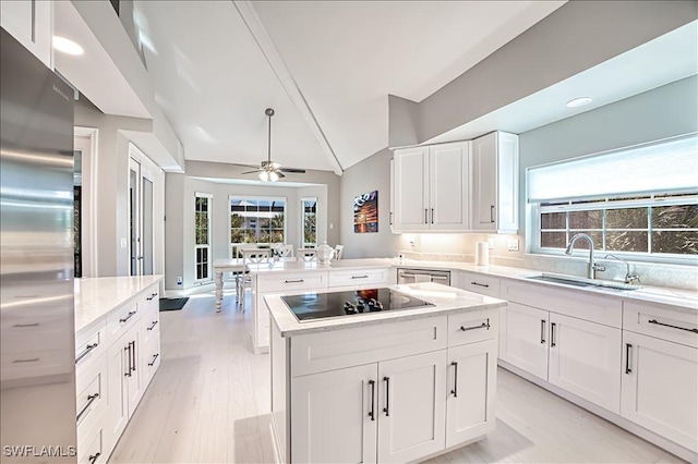 kitchen featuring sink, a center island, kitchen peninsula, stainless steel appliances, and white cabinets