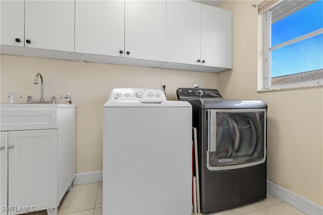 laundry room featuring separate washer and dryer, light tile patterned floors, and cabinets