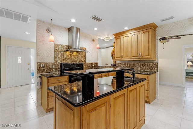 kitchen featuring stove, a center island, kitchen peninsula, dark stone counters, and wall chimney exhaust hood