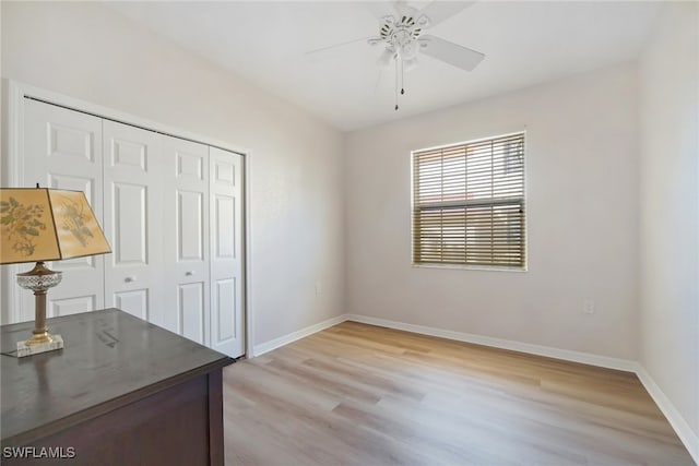 unfurnished office with baseboards, light wood-style floors, and ceiling fan