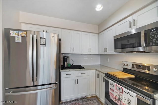 kitchen with stainless steel appliances, light stone countertops, white cabinets, and backsplash