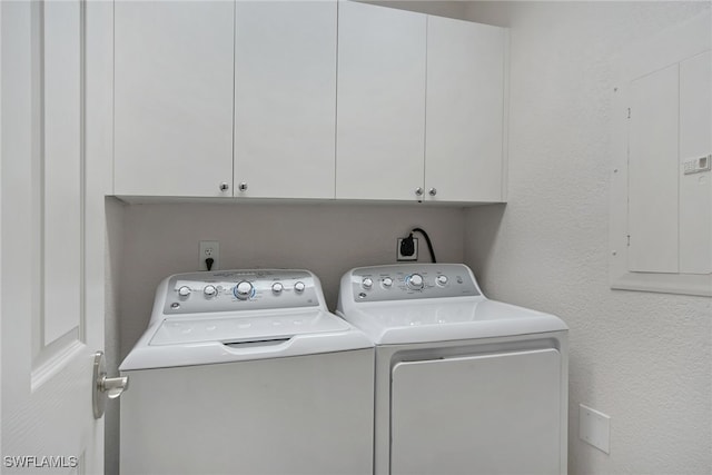 clothes washing area with washer and dryer, cabinets, and electric panel