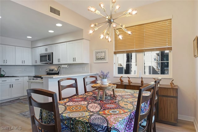 dining area featuring a chandelier, sink, and light hardwood / wood-style flooring