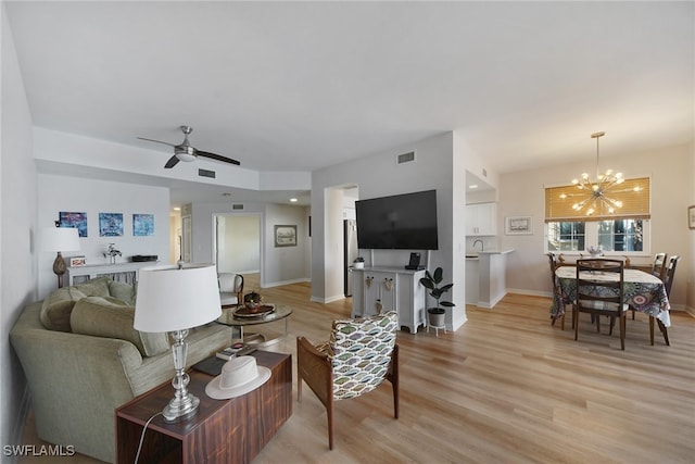 living room with ceiling fan with notable chandelier and light wood-type flooring