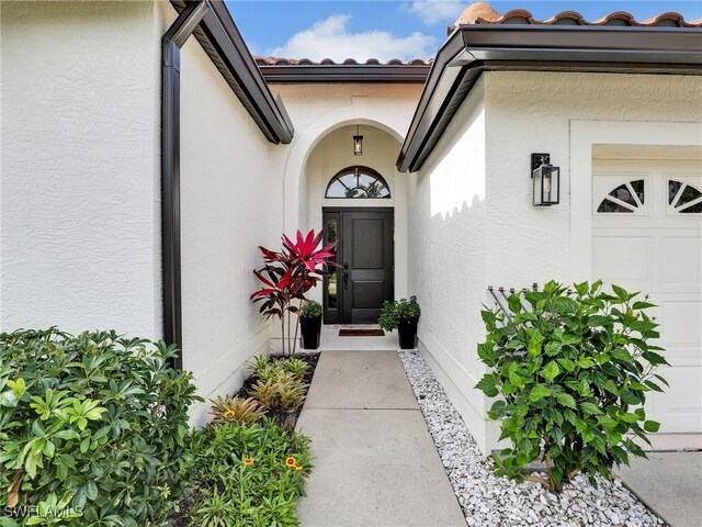 8850 Springwood Ct, Bonita Springs, FL 34135 - doorway to property featuring a tile roof, stucco siding, and an attached garage