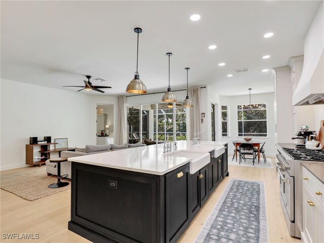 8850 Springwood Ct, Bonita Springs, FL 34135 - kitchen featuring dark cabinetry, high end stainless steel range, a center island with sink, a sink, and ceiling fan