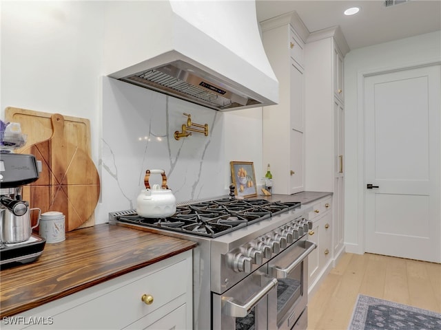 8850 Springwood Ct, Bonita Springs, FL 34135 - kitchen featuring double oven range, light wood finished floors, premium range hood, wood counters, and decorative backsplash