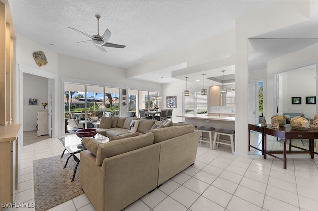 living room with ceiling fan, light tile patterned floors, and a textured ceiling