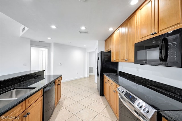 kitchen with dark stone countertops, light tile patterned floors, and black appliances